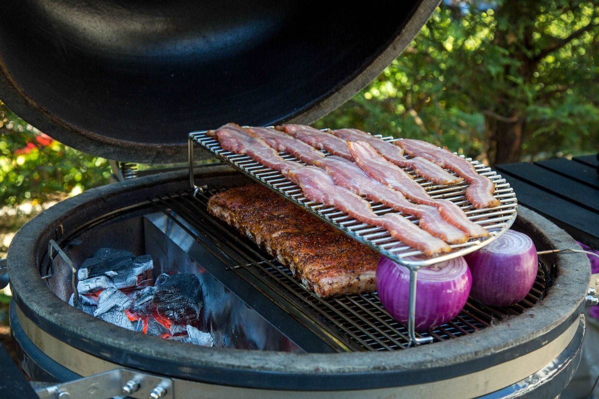 SnS Elevated Cooking Grate holding bacon above ribs on a kettle grill
